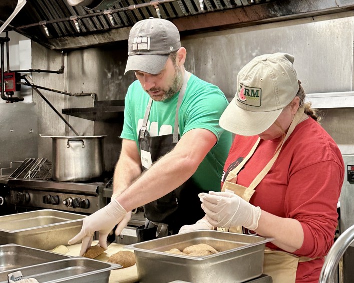 2 people cutting potatoes in school kitchenn