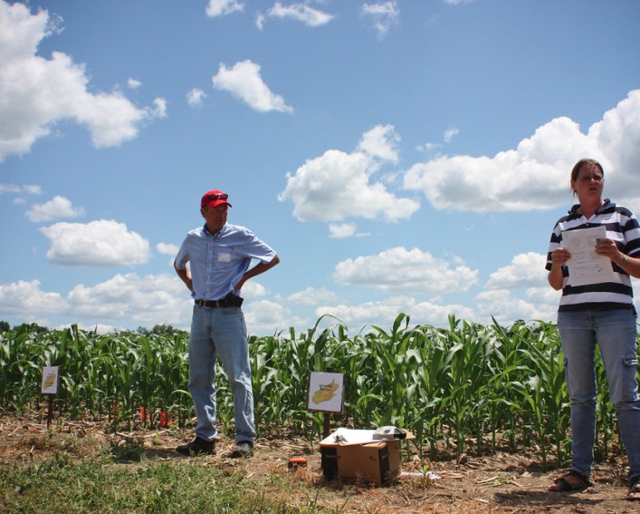 A man and a woman speak in a field.