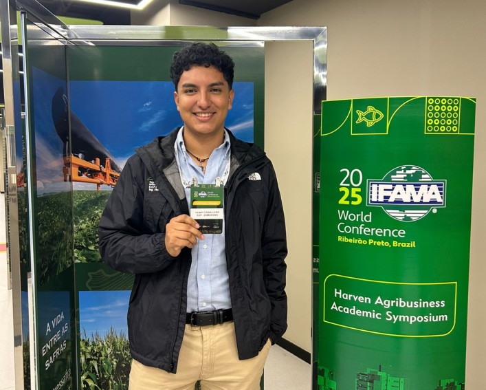 A man stands holding his badge at the entrance to a conference.