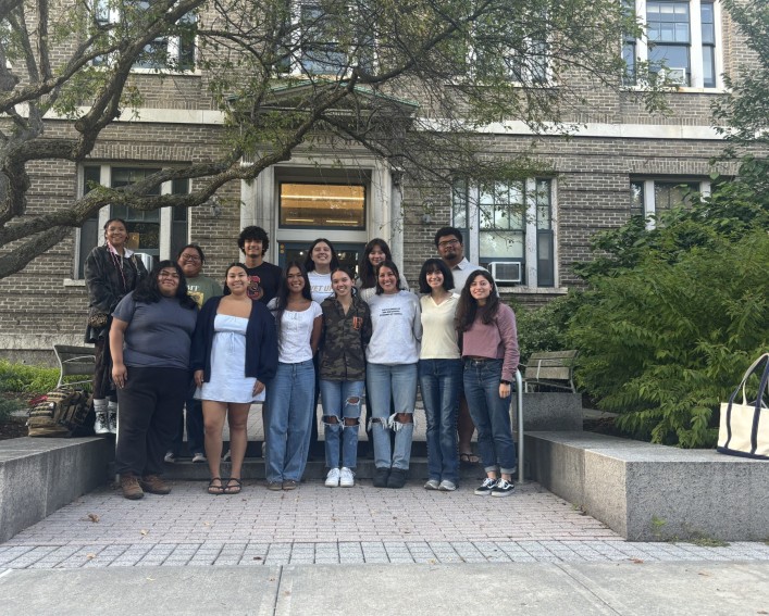 Student leaders stand smiling in front of Caldwell Hall.
