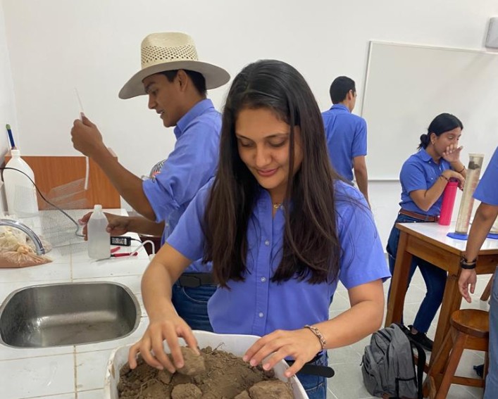 A woman touches soil in a bin.