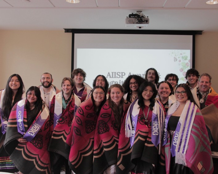 Students draped in blankets stand in a group.