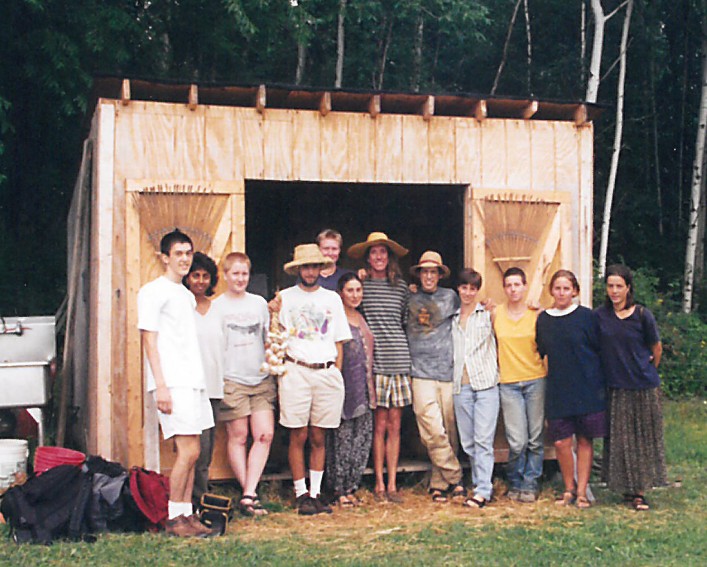 A group of people in front of the construction site of a small shed 