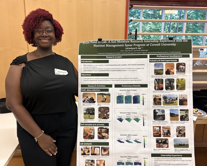 A woman poses next to her research poster.