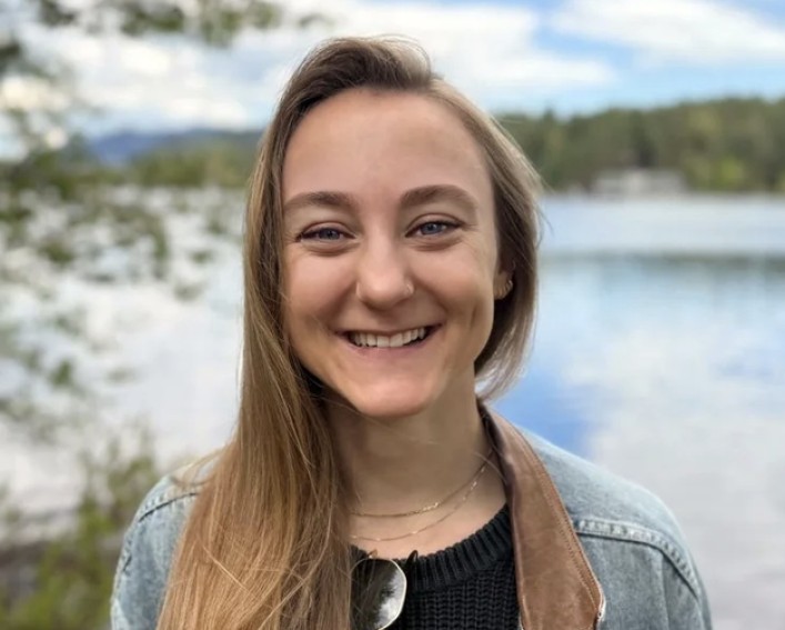 person smiling in front of a lake