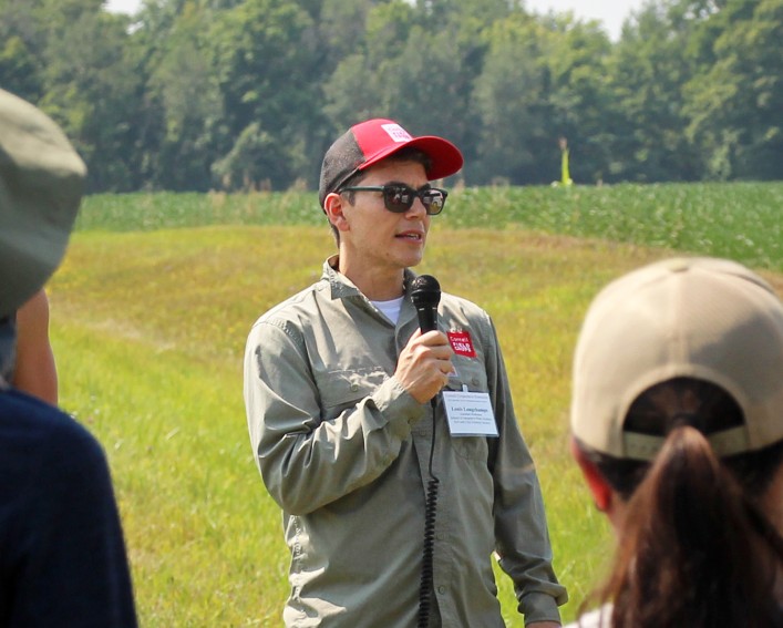 Louis Longchamp speaking to a group of people at a farm