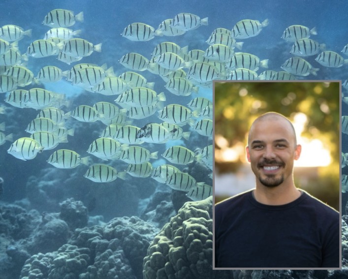 Man smiles in front of school of fish
