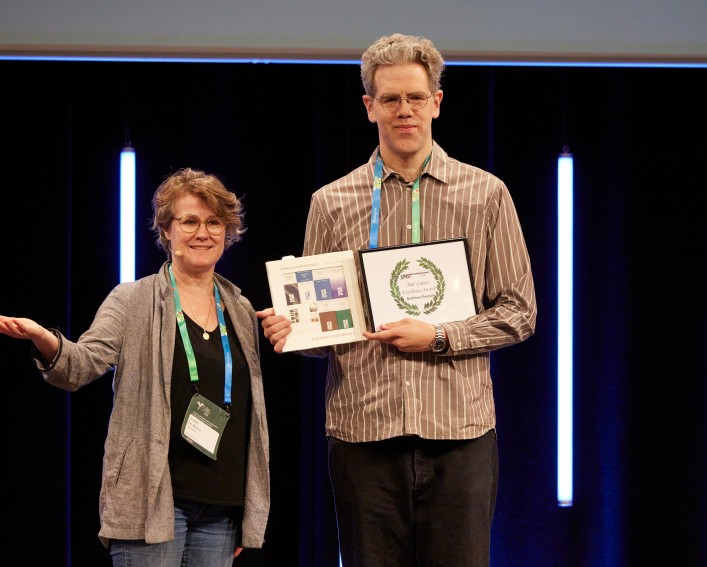 Man holds award next to presenter