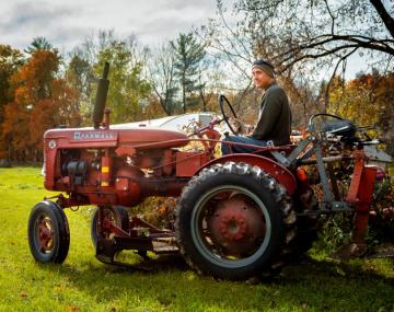 A man sitting on a red tractor outside 