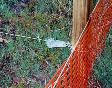 a ratchet mechanism a cable and orange plastic fencing