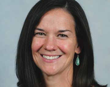 portrait of a woman with dark hair in front of a blue background