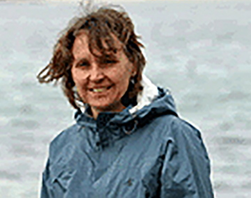 woman in a blue raincoat standing in front of the ocean
