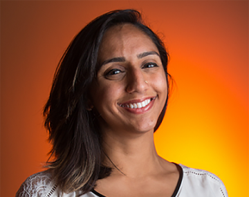 a woman in a white shirt smiling in front of an orange background