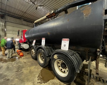 people in a garage looking at a manure tanker