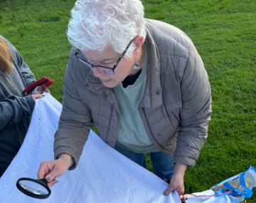 person examining a white cloth with a magnifying glass