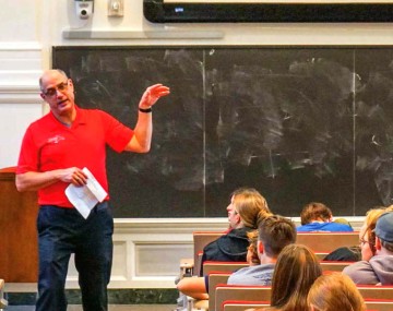Person in a red shirt ginig a lecture in front of a blackboard