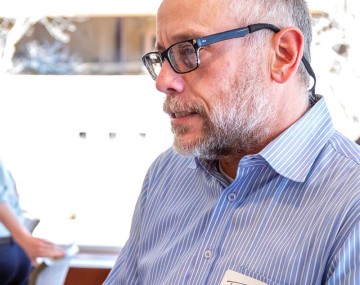 person in a blue shirt with grey hair and glasses