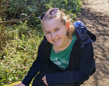 Girl smiling crouching down to touch the grass