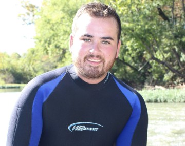 Photograph of a man in a wetsuit holding two large shells