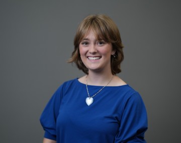 Student with brown hair wearing blue shirt with heart-shaped necklace