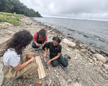 3 people kneeling on a beach looking at nets