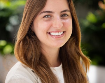 Student wearing a light beige blazer, standing outside smiling