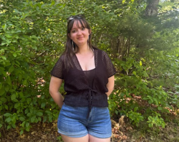 Aria stands smiling outside.