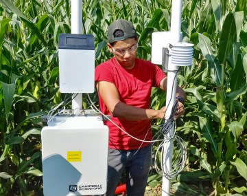 a man stands in a corn field with technology