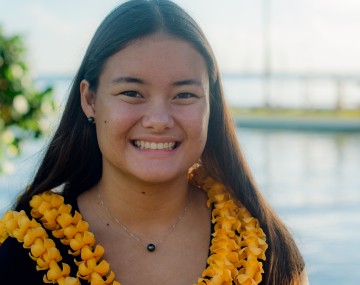 Joey stands in front of a harbor and smiles for the camera.