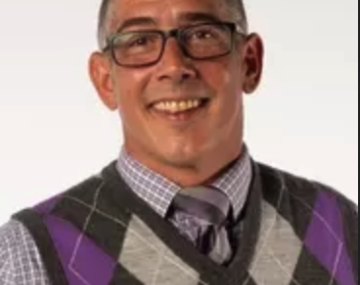 Photograph of a man wearing glasses and a sweater vest.