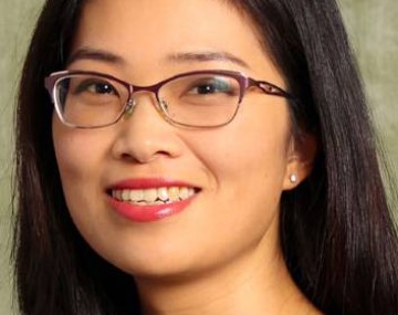 Photograph of a woman with longer dark hair and glasses.