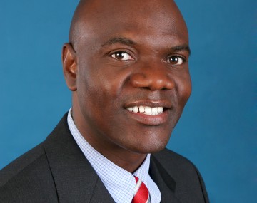 Professional portrait of a man wearing a suit jacket, shirt and red tie.