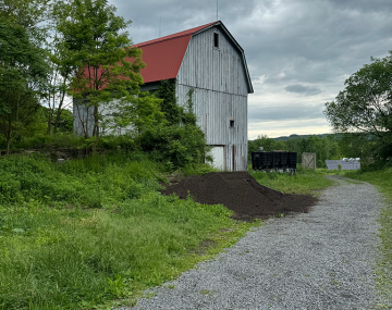 Barn near a farm road surrounded by trees and soil
