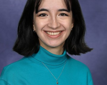 Celeste wears a teal turtleneck and smiles at the camera.