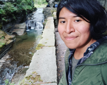 Jesse smiles in front of a waterfall.