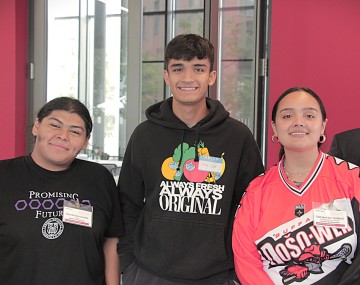 Three students smile for the camera.