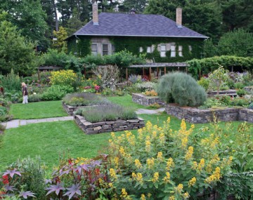 view of garden with paths and stone building in the background