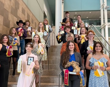 a group of young people stand together holding ribbons and trophies