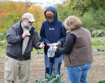 three people stand in a garden