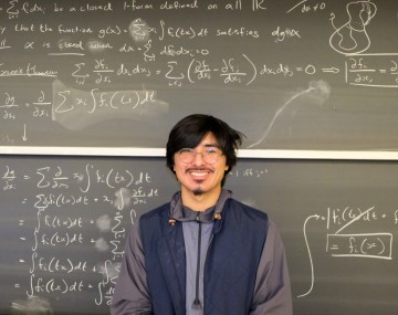 Roman stands in front of a chalkboard.