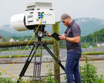 a man looks at a gas sensor set up by a manure pit