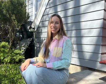 Jordan sits on a step outside a blue building.