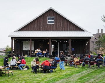 people eating and making music in front of a barn