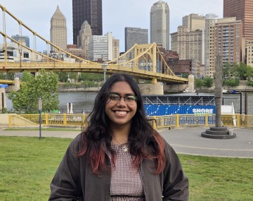 person with long dark hair in front of a cityscape