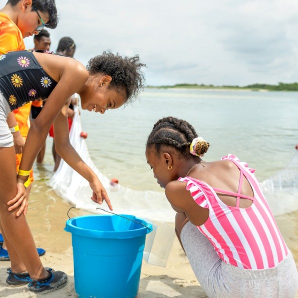 Kassidy Bates (left), 10, and Genayah Desousa, 10, from Hempstead, New York, point to fish and crabs hauled in from the bay at Jones Beach State Park.